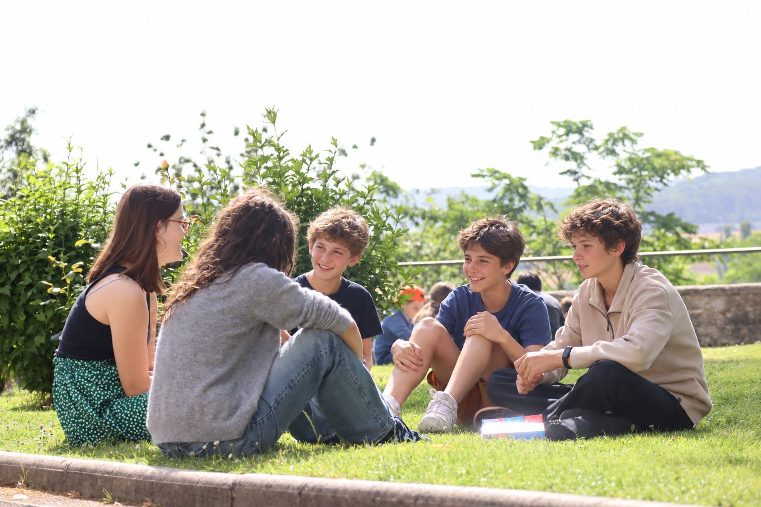 Des adolescents discutent, assis dans l'herbe